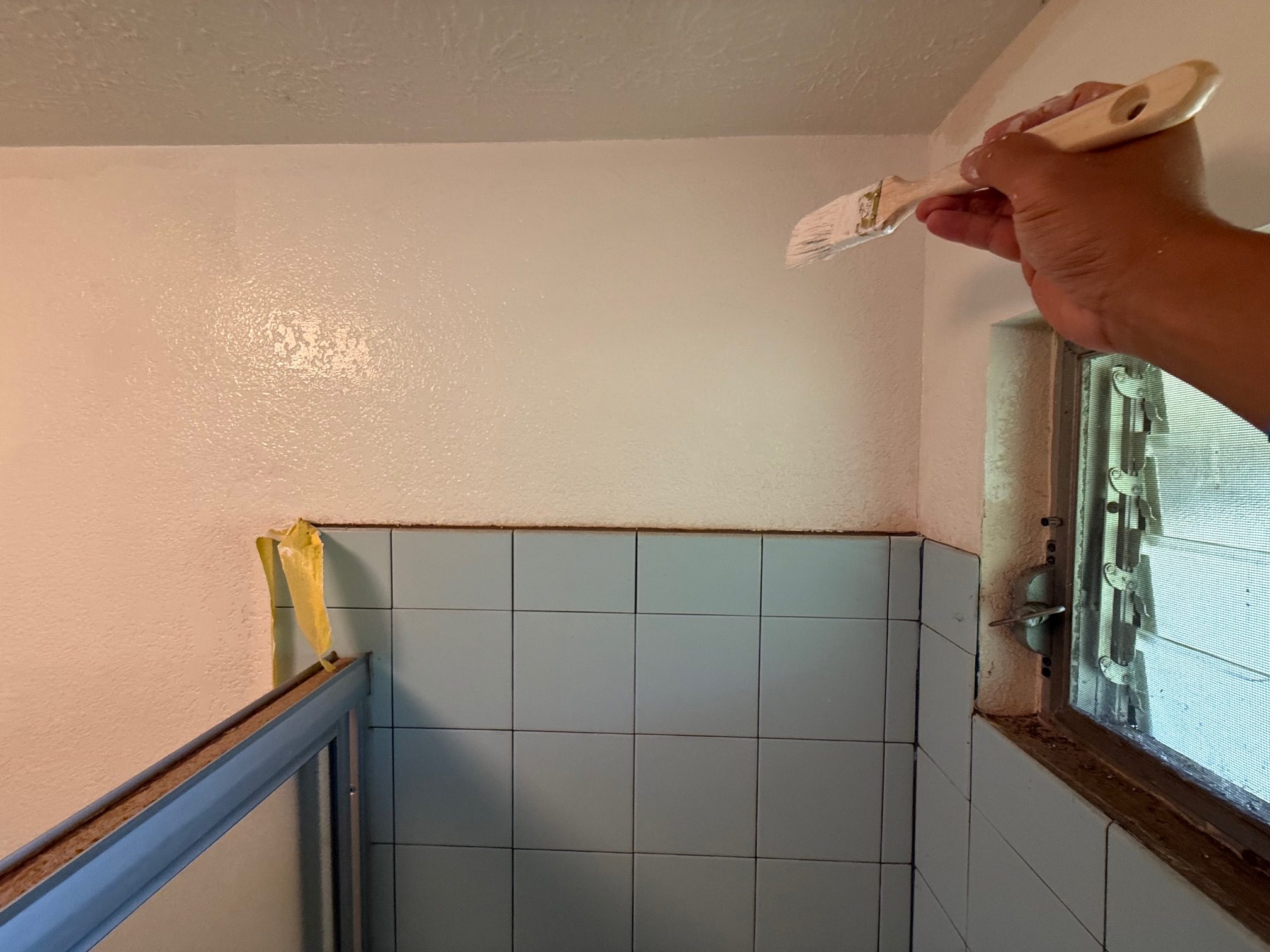 Getting on step-stool and painting around the tub area with semi-gloss Benjamin Moore paint from City Mill ($60/gallon plus tax). Need to redo the window ledge as it's falling apart. 